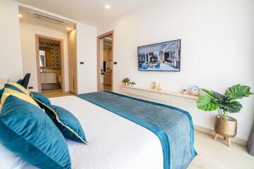 Modern bedroom with blue bedding and wall-mounted TV