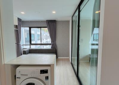 Modern apartment with open layout including laundry area, living space, and glass partition