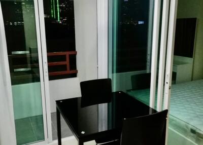 Modern dining area with glass table and black chairs near windows with city view