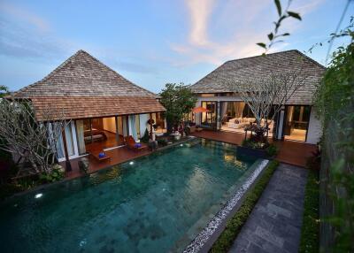 Exterior view of a luxury villa with a swimming pool at dusk