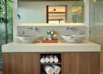 Modern bathroom with double sink, large mirror, and rolled towels