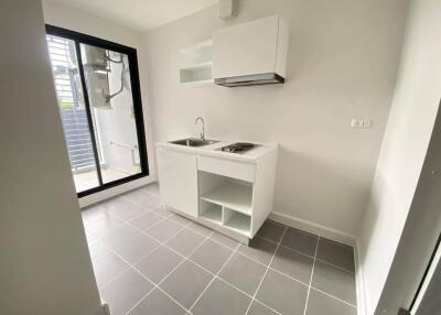 Modern compact kitchen with white cabinetry and stainless steel sink