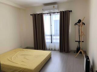 bedroom with bed, curtained window, and clothing stand