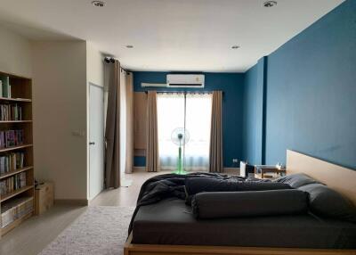 Spacious bedroom with bed, window, and bookshelves