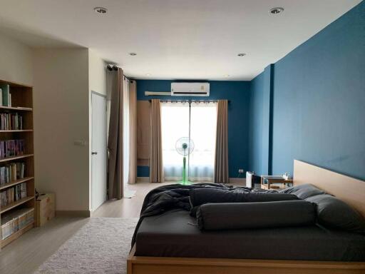 Spacious bedroom with bed, window, and bookshelves