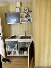 Compact kitchen area with wall-mounted TV and storage shelves