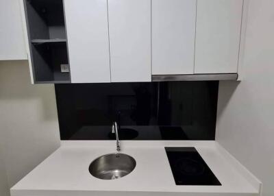 Compact modern kitchenette with white cabinets and black backsplash