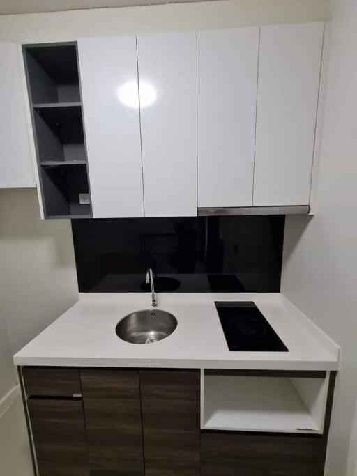 Compact modern kitchenette with white cabinets and black backsplash