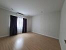 Spacious empty bedroom with window and dark curtains