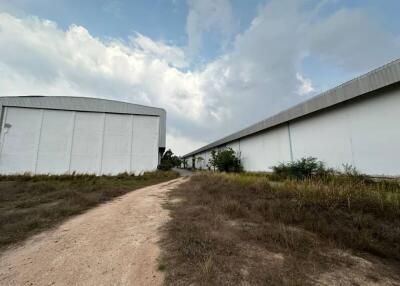 Two large industrial warehouse buildings with a dirt path between them