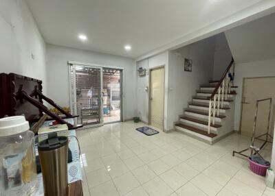 A photo of a main living space with stairs leading to the upper floor, a metal gate, and a tiled floor.