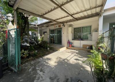 Exterior view of a single-story house with a covered patio and surrounding greenery