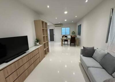 Modern living room with sofa, TV, dining table, and storage units