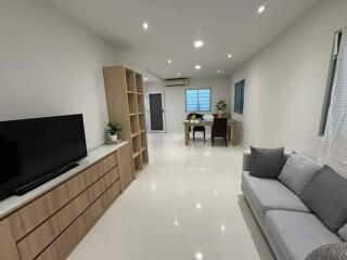 Modern living room with sofa, TV, dining table, and storage units