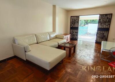 Spacious living room with a white sectional sofa and wooden flooring