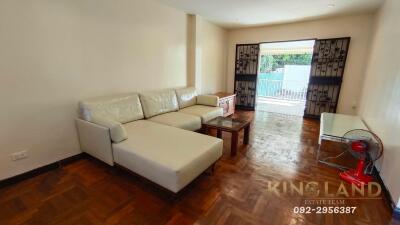 Spacious living room with a white sectional sofa and wooden flooring