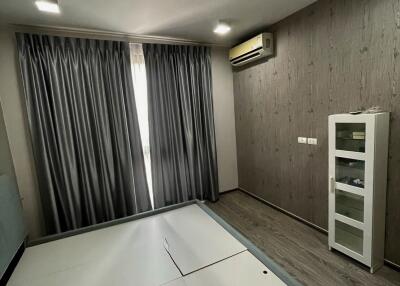 Spacious bedroom with large window, modern flooring, built-in air conditioning, and storage cabinet