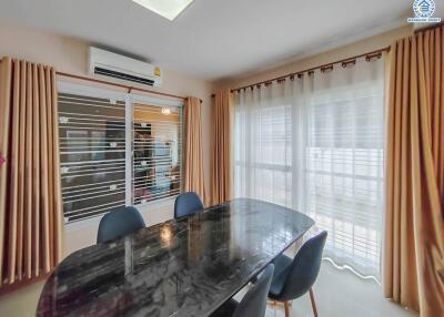 Bright dining room with a modern table and chairs, large windows, and curtains.