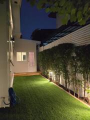 Modern backyard with artificial grass and evening lighting