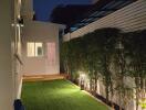 Modern backyard with artificial grass and evening lighting