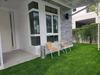 Modern house exterior with patio furniture on artificial grass lawn