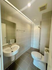 Modern bathroom with tiled walls, sink, toilet, and walk-in shower.