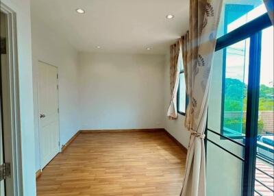 Well-lit bedroom with large windows and wooden flooring