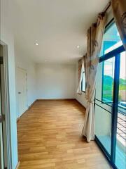 Well-lit bedroom with large windows and wooden flooring