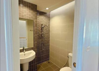 Modern bathroom with tiled walls and floor, featuring a sink, toilet, and shower