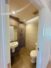 Modern bathroom with tiled walls and floor, featuring a sink, toilet, and shower