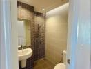 Modern bathroom with tiled walls and floor, featuring a sink, toilet, and shower