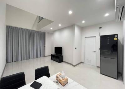 Modern living room with TV, dining table, and refrigerator