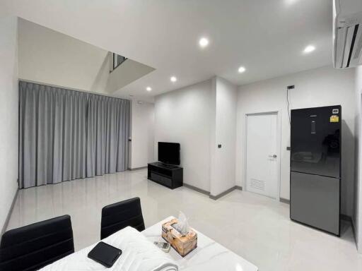 Modern living room with TV, dining table, and refrigerator