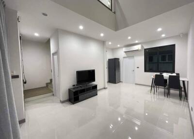 Modern living room with high ceiling, large windows, and minimalist furniture