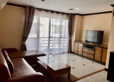 Living room with large windows, sofa, wooden table, and TV cabinet