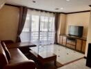 Living room with large windows, sofa, wooden table, and TV cabinet