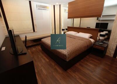 Bedroom with wooden flooring, double bed, study table, and air conditioner