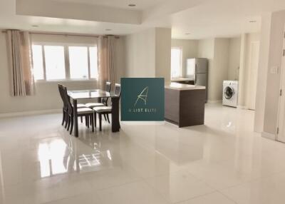 Spacious main living area with dining table, kitchen island, refrigerator, and washing machine