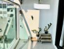 Modern balcony with glass railing, potted plants, and an AC unit