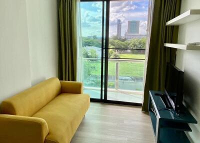 Bright living room with a large window, green view, yellow couch, and TV