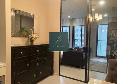 A modern living room with a dresser, mirror, and glass door leading to a balcony