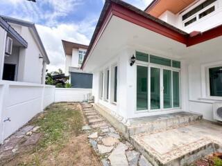 Exterior view of a house with a large glass door and side garden