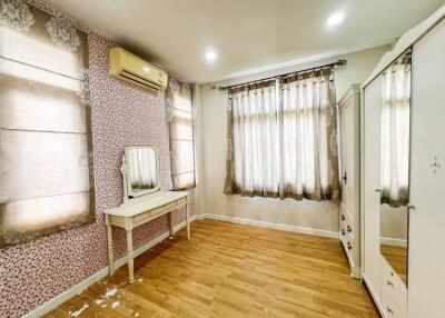 image of a bedroom with wooden flooring, a vanity table, air conditioning, and large windows with curtains