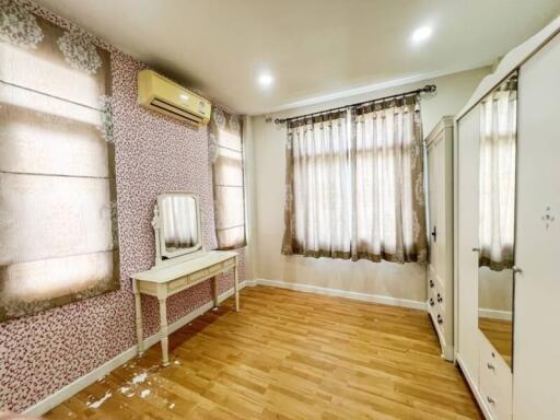 image of a bedroom with wooden flooring, a vanity table, air conditioning, and large windows with curtains