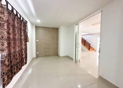 Spacious living room with tiled floor and decorative curtains, connected to a staircase