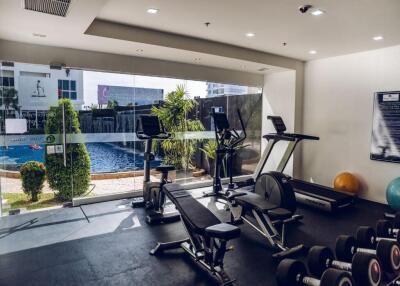 Well-equipped gym with cardio machines and weights, overlooking a pool area