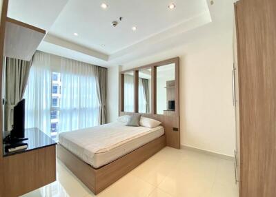 Modern bedroom with large windows, a comfortable bed, and wooden furniture