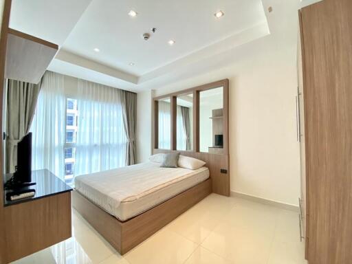 Modern bedroom with large windows, a comfortable bed, and wooden furniture