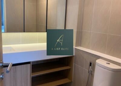 Modern bathroom with beige tiles, vanity mirror, and storage shelves