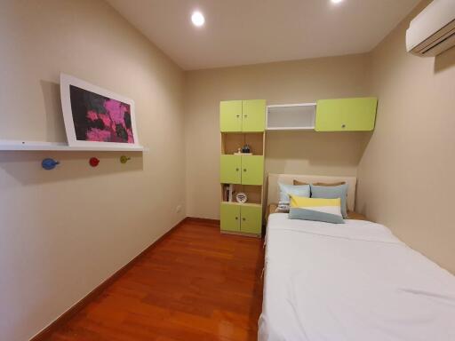 A cozy bedroom with wooden flooring, single bed, wall-mounted storage, and minimal decor.